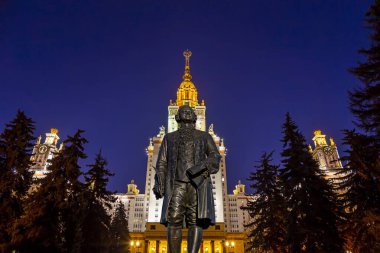 Rusya 'nın başkenti Sparrow Hills' teki Moskova Devlet Üniversitesi 'nin (MSU) ana binasının yanından Mikhail Vasilyevich Lomonosov anıtının (sonbahar akşamı) görüntüsü.  