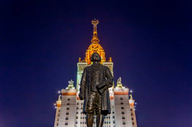 Rusya 'nın başkenti Sparrow Hills' teki Moskova Devlet Üniversitesi 'nin (MSU) ana binasının yanından Mikhail Vasilyevich Lomonosov anıtının (sonbahar akşamı) görüntüsü.  