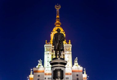 Rusya 'nın başkenti Sparrow Hills' teki Moskova Devlet Üniversitesi 'nin (MSU) ana binasının yanından Mikhail Vasilyevich Lomonosov anıtının (sonbahar akşamı) görüntüsü.  