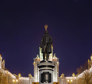 Rusya 'nın başkenti Sparrow Hills' teki Moskova Devlet Üniversitesi 'nin (MSU) ana binasının yanından Mikhail Vasilyevich Lomonosov anıtının (sonbahar akşamı) görüntüsü.  