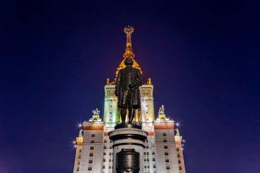 Rusya 'nın başkenti Sparrow Hills' teki Moskova Devlet Üniversitesi 'nin (MSU) ana binasının yanından Mikhail Vasilyevich Lomonosov anıtının (sonbahar akşamı) görüntüsü.  