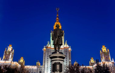 Rusya 'nın başkenti Sparrow Hills' teki Moskova Devlet Üniversitesi 'nin (MSU) ana binasının yanından Mikhail Vasilyevich Lomonosov anıtının (sonbahar akşamı) görüntüsü.  