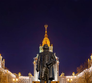 Rusya 'nın başkenti Sparrow Hills' teki Moskova Devlet Üniversitesi 'nin (MSU) ana binasının yanından Mikhail Vasilyevich Lomonosov anıtının (sonbahar akşamı) görüntüsü.  