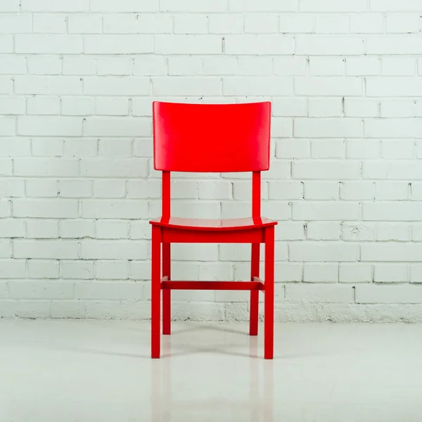 Red wooden chair in empty white room against a brick wall — Stock Photo, Image