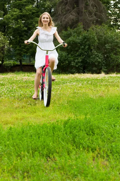 Young beautiful woman cycling in the park — Stock Photo, Image