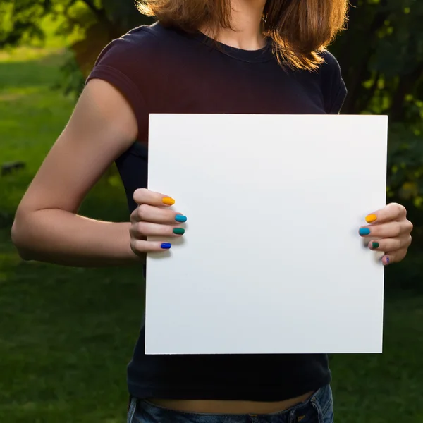 Ung flicka håller vit blank papper mot bakgrund av Shopaholic — Stockfoto