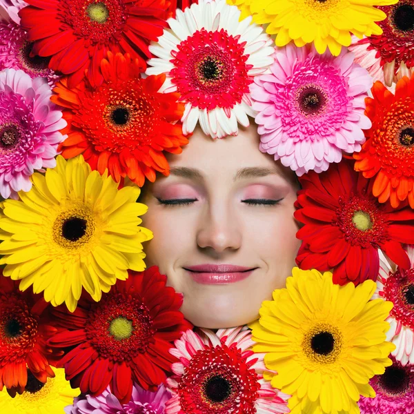 Menina bonita feliz com flores em torno de seu rosto — Fotografia de Stock