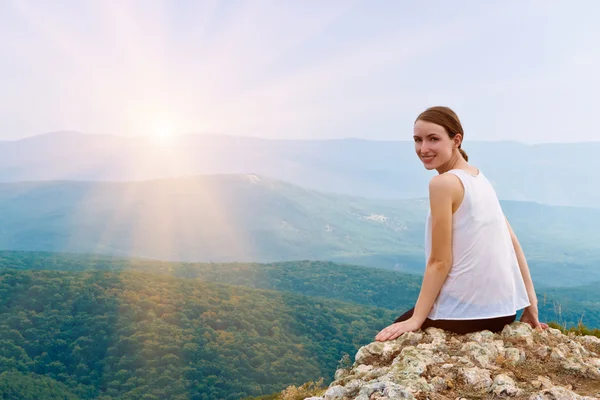 Felice sorridente ragazza seduta su una scogliera — Foto Stock