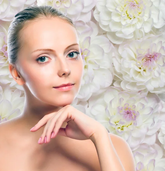 Young girl against white flowers background — Stock Photo, Image