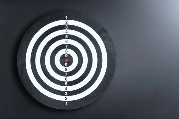 Darts board on a black wall with light spot — Stock Photo, Image