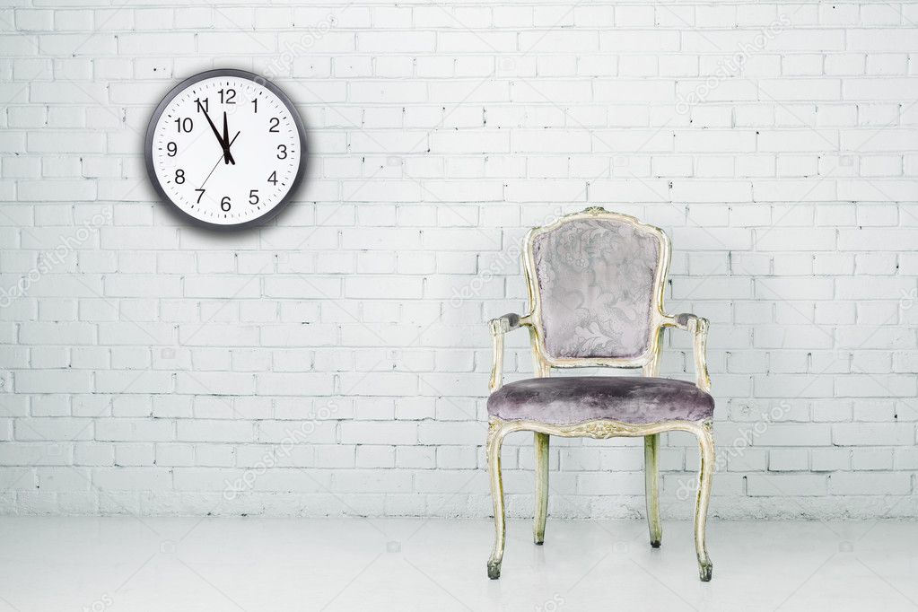 Vintage chair against white brick wall with clock