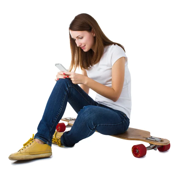 Žena sedí na skateboardu a pomocí smartphonu. — Stock fotografie