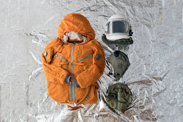 Plochá poloha složených astronautů oranžový skafandr, vesmírná přilba a skafandry příslušenství na stříbrném pozadí — Stock fotografie