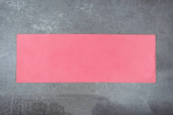 Różowa mata do jogi na betonowej podłodze. Mata fitness jest rozłożona na cementowej podłodze — Zdjęcie stockowe