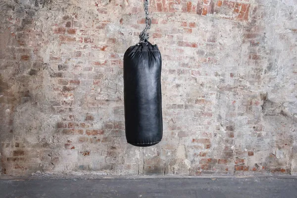 Black punching bag with grunge brick wall with blank space — Stock Photo, Image