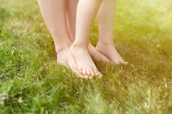 Closeup of woman and toddler kid barefeet on green grass. Mother and toddler kid walking on the grass barefeet — Stock Photo, Image