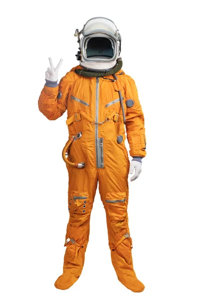 Astronauta con un traje espacial naranja y casco que muestra un gesto de victoria en la mano aislado sobre fondo blanco. Cosmonauta irreconocible con una señal de victoria en la mano — Foto de Stock