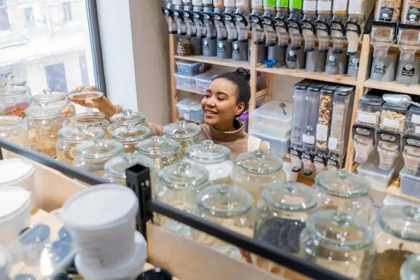 Heureuse femme afro-américaine achetant des aliments biologiques dans une épicerie durable zéro déchet. Jeune femme choisissant de la nourriture dans l'épicerie locale. — Photo