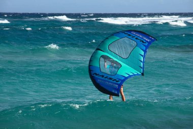 BOCA GRANDI, ARUBA - 17 Aralık 2020: Karayip adası Aruba 'daki Boca Grandi sahilinde Naish Wing-Sörfçü uçurtması olan kişi (Seçici Odak, sörfçü ve uçurtmaya odaklan)