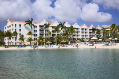 ORANJESTAD, ARUBA - 4 Aralık 2021: Rönesans Okyanusu Suit Oteli yüzme havuzu ve palmiye ağaçları ve sahil sandalyeleriyle dolu kumlu sahil bölgesi Karayip adası Aruba 'daki Oranjestad' da yer alıyor.