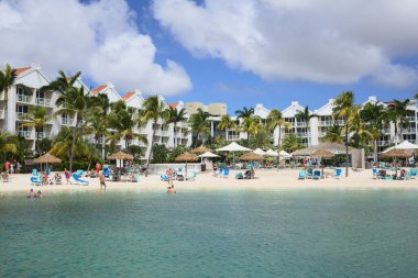 ORANJESTAD, ARUBA - 4 Aralık 2021: Rönesans Okyanusu Suit Oteli yüzme havuzu ve palmiye ağaçları ve sahil sandalyeleriyle dolu kumlu sahil bölgesi Karayip adası Aruba 'daki Oranjestad' da yer alıyor.