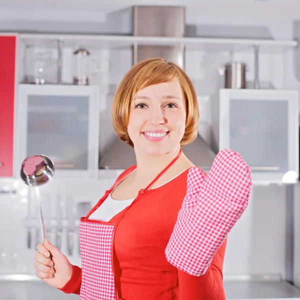 Beautiful young housewife in kitchen holding ladle — Stock Photo, Image