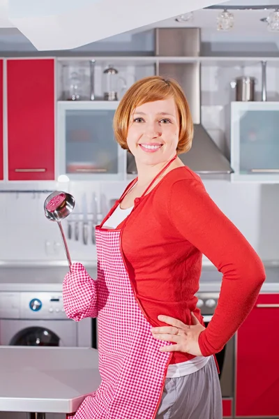 Beautiful young housewife in kitchen holding ladle — Stock Photo, Image