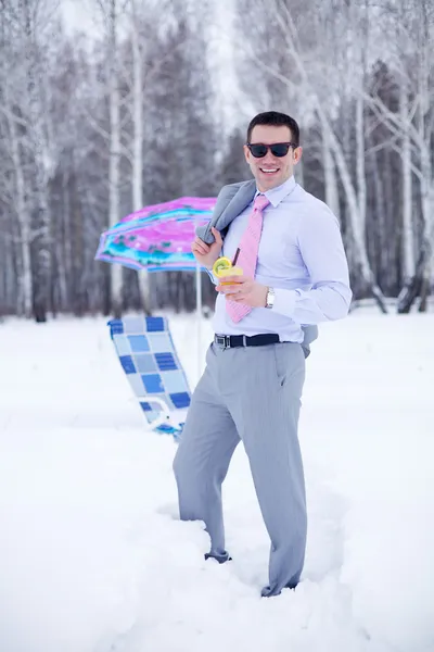 Businessman at winter forest holding cocktail near beach bed and sunshade — Stock Photo, Image