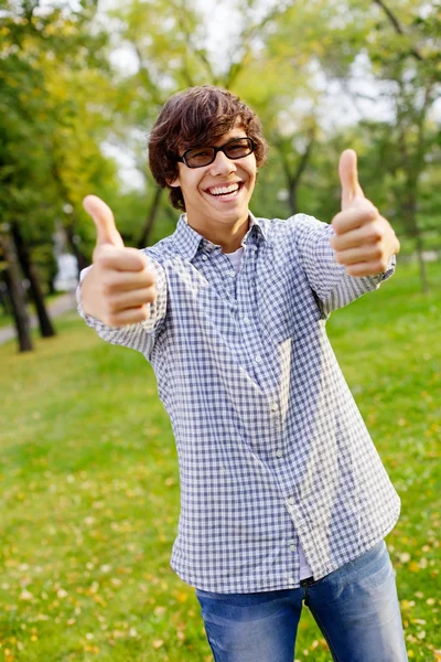 Happy guy showing thumbs up in park — Stock Photo, Image