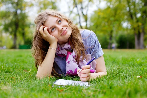 Tienermeisje huiswerk maken in park — Stockfoto