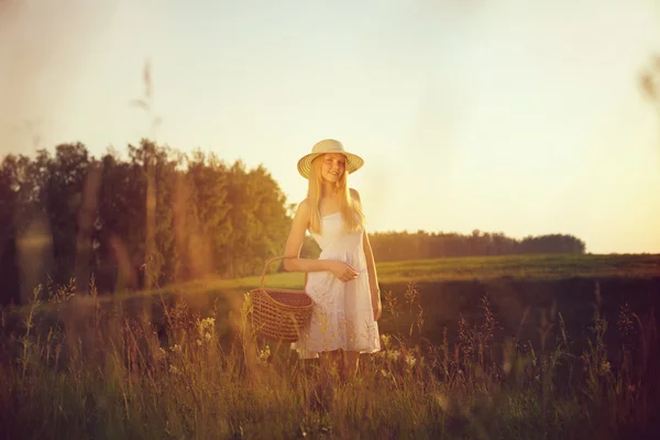 Pretty young girl with picnic basket in field — Stock Photo, Image