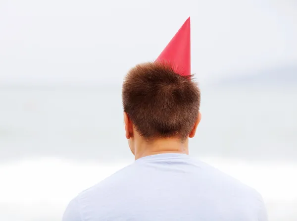 Man in de rode hoed in de buurt van zee van achter — Stockfoto