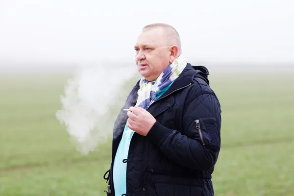 Старший курит над туманным полем — стоковое фото