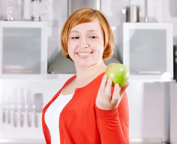 Redhead housewife with apple in kitchen — Stock Photo, Image