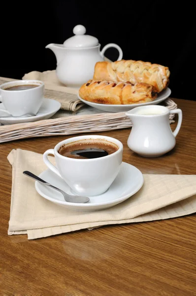 Una taza de café negro con un lechero con una bandeja de pasteles —  Fotos de Stock