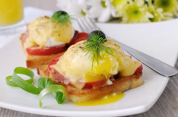 Eggs Benedict with ham and tomato on toast with cheese — Stock Photo, Image