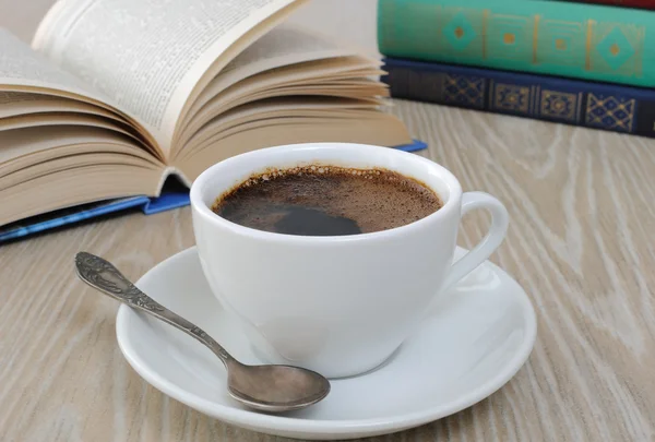 En kopp kaffe på et bord blant bøker. – stockfoto