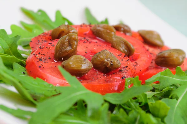Salad with fresh tomatoes, capers and arugula — Stock Photo, Image