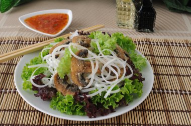 Rice noodles with mushrooms in breadcrumbs in lettuce leaves clipart