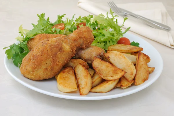 Chicken drumsticks with breadcrumbs with potatoes and salad — Stock Photo, Image