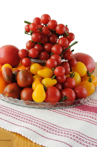 Different varieties of tomatoes in a glass vase — Stock Photo, Image