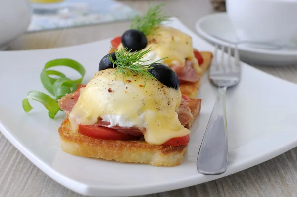 Яйца Бенедикт с ветчиной и помидорами на тосте с сыром — стоковое фото
