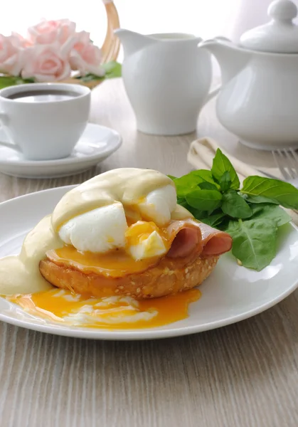 Boiled eggs (poached) with ham on a bun with sauce — Stock Photo, Image