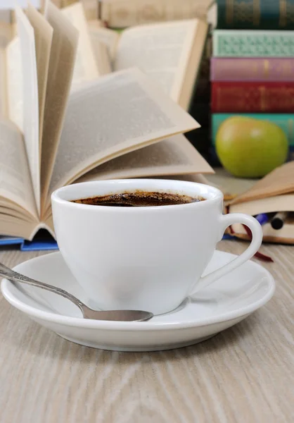 Ένα φλιτζάνι καφέ σε ένα τραπέζι μεταξύ βιβλία — Φωτογραφία Αρχείου