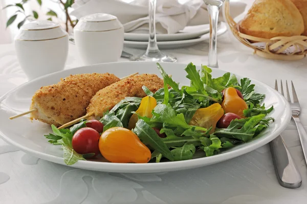 Garnering van arugula en tomaten met kippenschnitzel — Stockfoto