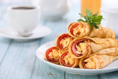 Bir dilim jambonlu ve çırpılmış yumurtalı ev yapımı incecik krepler masanın üstünde. Harika kahvaltı fikri..