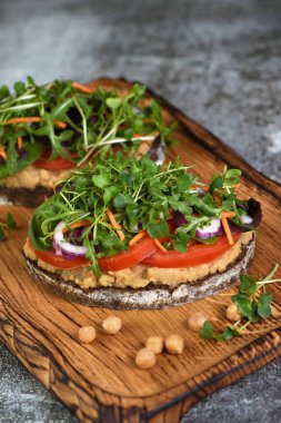  Nohut humuslu rustik ekmek, domates dilimleri, marul ve mikroyeşillik karışımı. Vejetaryen kahvaltısı. 