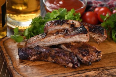 Ahşap tabakta barbekü soslu leziz ızgara domuz eti, otlar ve sebzeler.