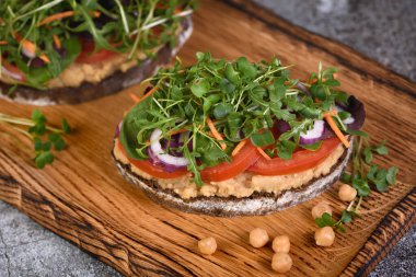  Nohut humuslu rustik ekmek, domates dilimleri, marul ve mikroyeşillik karışımı. Vejetaryen kahvaltısı. 