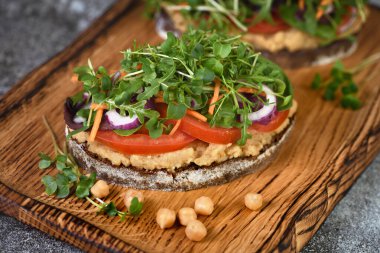 Nohut humuslu rustik ekmek, domates dilimleri, marul ve mikroyeşillik karışımı. Vejetaryen kahvaltısı. 